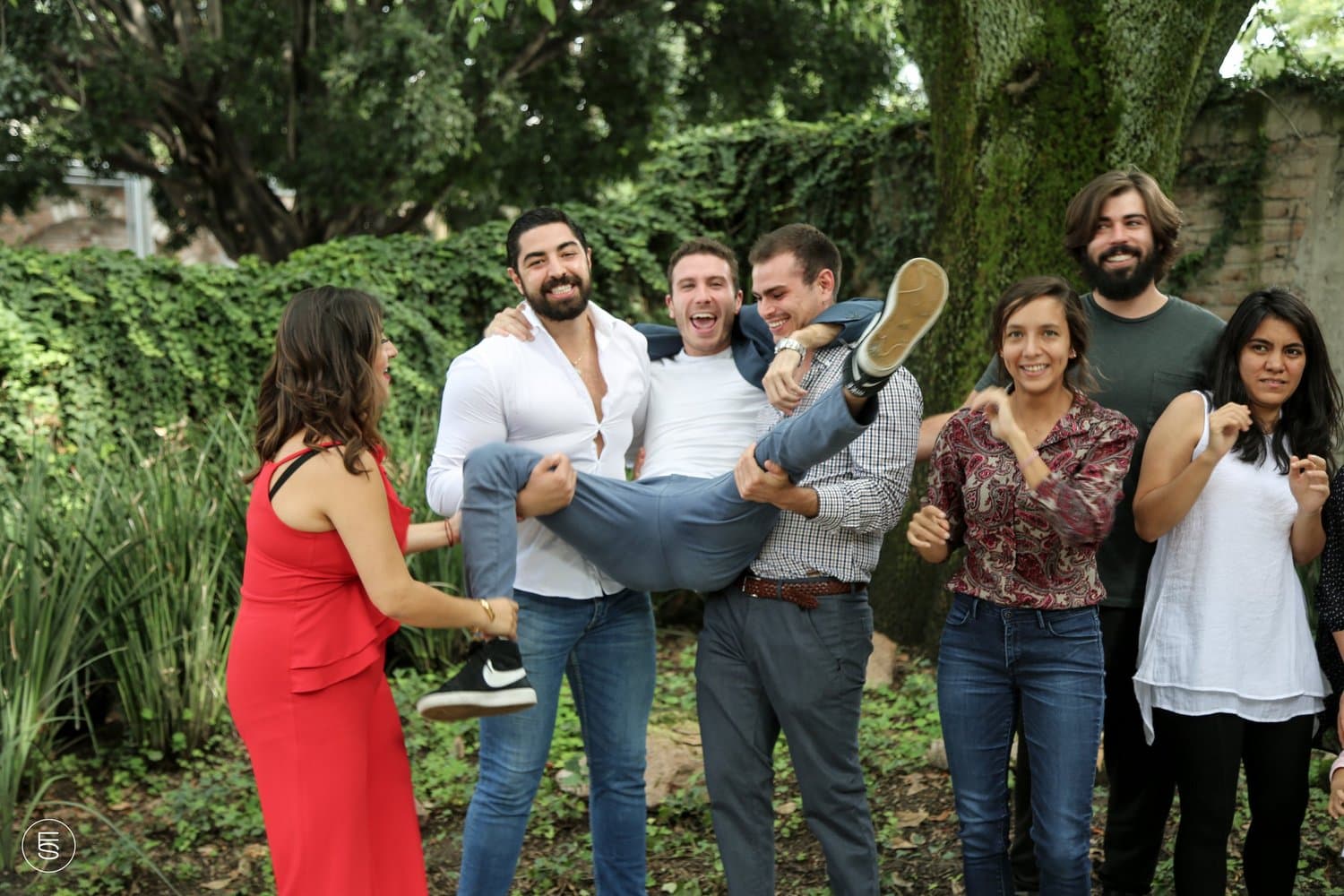 Équipe de startup soulevant un collègue dans un jardin
