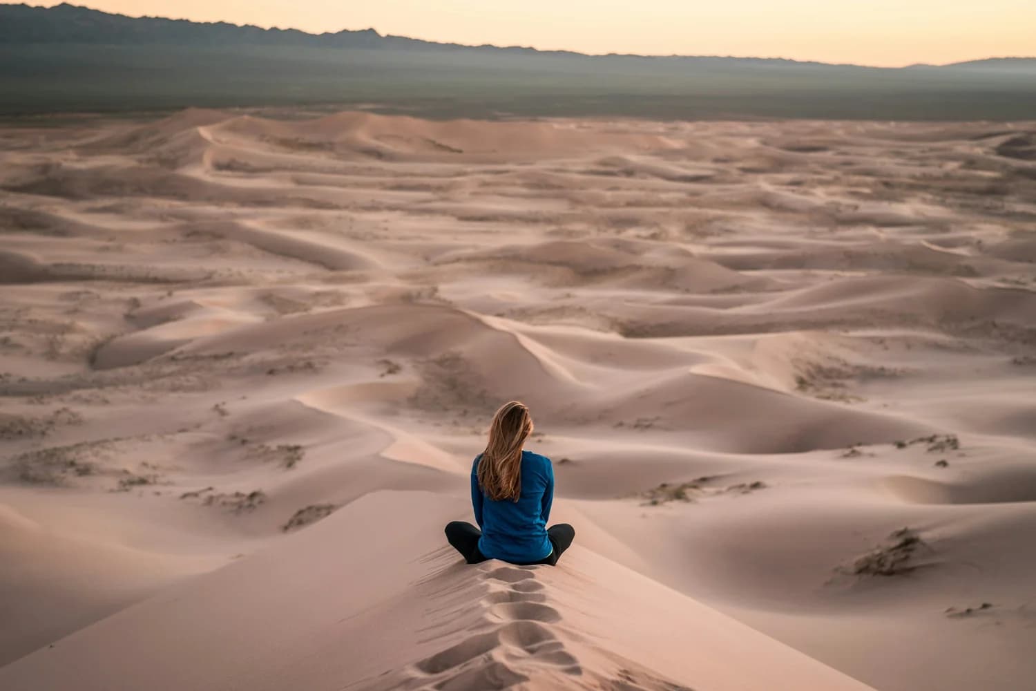 Femme assise en méditation sur une dune de désert