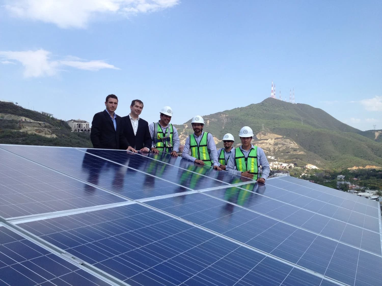Équipe posant devant des panneaux solaires en montagne